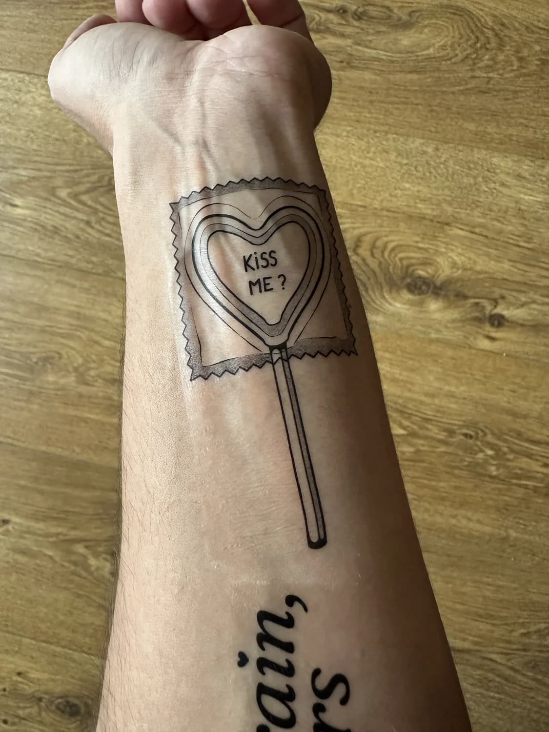 Playful heart lollipop line tattoo on a wrist